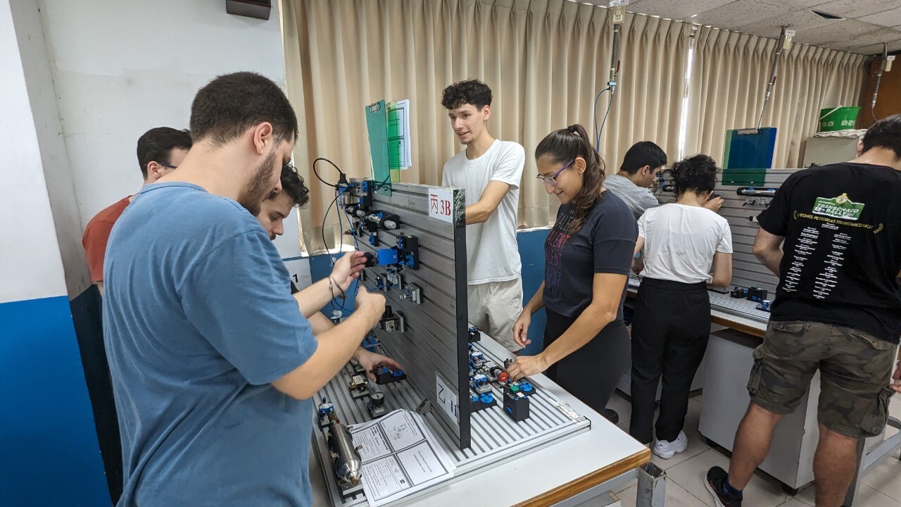 Taiwan-Paraguay Polytechnic University students adjust the forward and backward movements of pneumatic cylinders, control speed loops, and delay circuits.