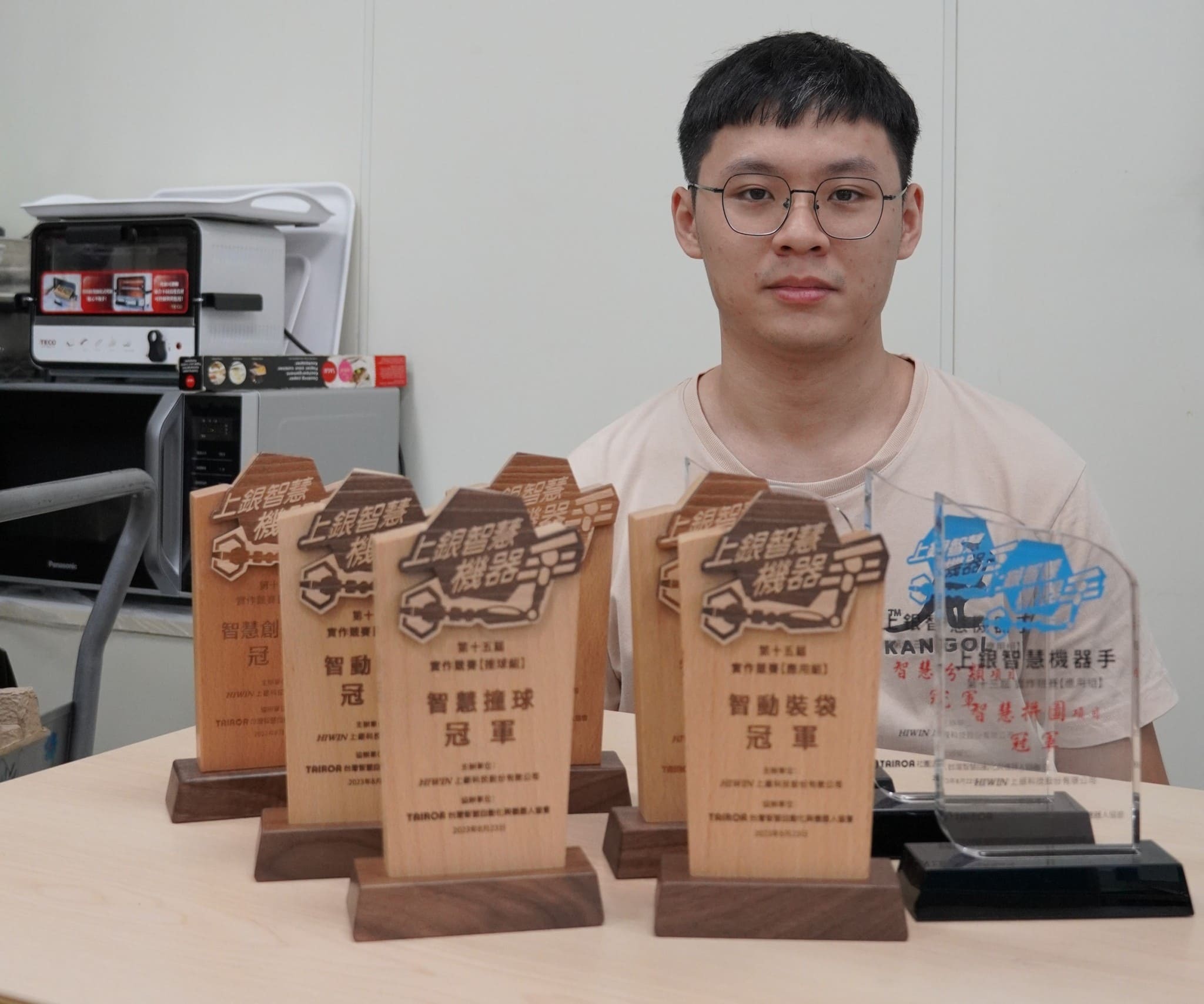 Taiwan Tech's first-year electrical engineering graduate student, Bo-Sheng Huang, captured in a group photo with his medals from the Hiwin Intelligence Robotic Competition, a feat he has achieved for three consecutive years.